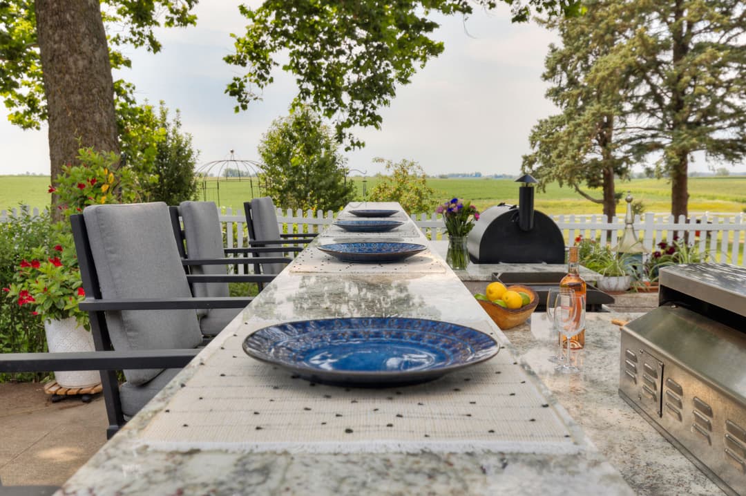Outdoor dining setup with blue plates, grill, and scenic countryside view.